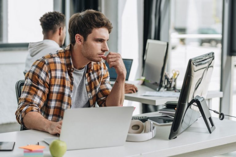 Homme devant deux écrans de PC